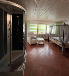 a bathroom with a shower and a bed and a chair at Allgäu Pension "Ab in den Süden" in Bernbeuren