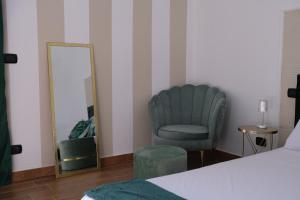 ein Schlafzimmer mit einem Stuhl und einem Spiegel in der Unterkunft SUITE LA VILLA in Statte