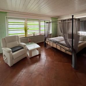 a bedroom with a bed and a chair and a table at Allgäu Pension "Ab in den Süden" in Bernbeuren