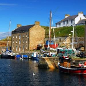 a group of boats docked in a harbor with a building at Harbour Side, Luxury, Twin Level Loft in Burghead
