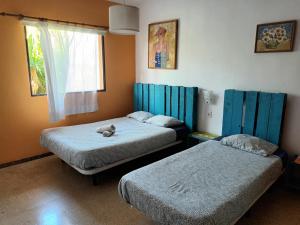 ein Zimmer mit 2 Betten und einem ausgestopften Tier auf dem Bett in der Unterkunft Lagarto Hostel Tenerife in Valle de Guerra