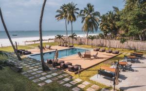 una piscina junto a una playa con palmeras en LalaGalu - Beachfront EcoCabins en Diani Beach