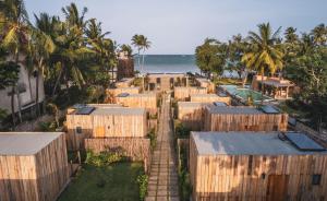 an aerial view of wooden buildings and the beach at LalaGalu - Beachfront EcoCabins in Diani Beach