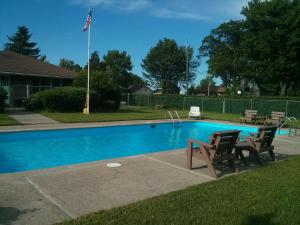 a swimming pool with two chairs and an american flag at Port Motel in Port Colborne