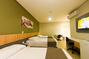 a hotel room with two beds and a flat screen tv at Hotel Plaza Garden in Cascavel