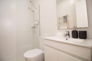een witte badkamer met een toilet en een douche bij Comfortable getaway in Medieval Castro Marim in Castro Marim