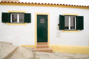 een wit gebouw met groene ramen en een deur bij Comfortable getaway in Medieval Castro Marim in Castro Marim