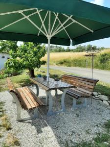 a picnic table with a green umbrella and a bench at Ferienhaus Bayerlipp in Scheßlitz