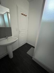 Baño blanco con lavabo y espejo en Studio avec balcon au centre de Bagnères, en Bagnères-de-Bigorre