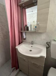 ein Badezimmer mit einem Waschbecken und einem rosa Duschvorhang in der Unterkunft Smile studio in Drama