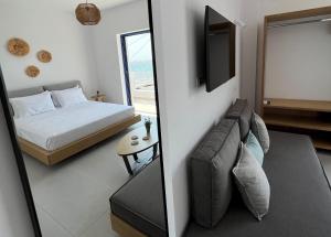 a bedroom with a bed and a couch and a television at Kythera Beach Apartments in Diakofti