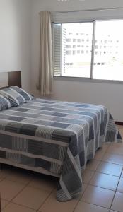 um quarto com uma cama com um cobertor azul e branco em Apto dois quartos pertinho da praia em Florianópolis