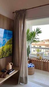 a living room with a large window and a television at Villa PF Village - Praia do Lord in Praia do Forte