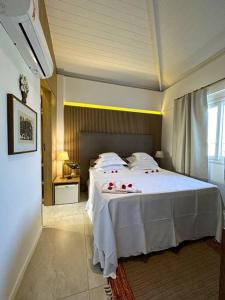 a bedroom with a white bed with red roses on it at Villa PF Village - Praia do Lord in Praia do Forte