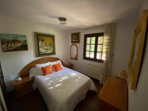ein Schlafzimmer mit einem weißen Bett und orangefarbenen Kissen in der Unterkunft Casa del Pintor Antonio Mesa in Mombeltrán + 54 Fotos