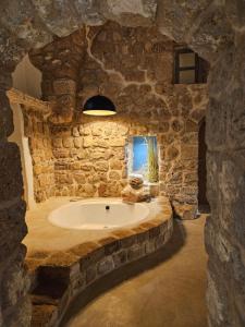 un bagno in pietra con vasca in un muro di pietra di Akotika boutique a ‘Akko
