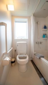 a white bathroom with a toilet and a window at Serenity Chalet, walk to the lifts Happoone Ski Resort in Hakuba