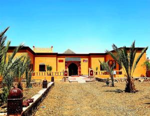 un edificio de naranjos con palmeras delante de él en Riad family en Merzouga