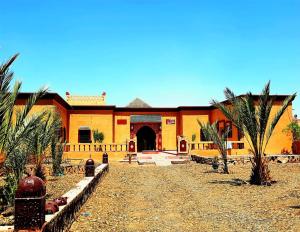 an orange building with palm trees in front of it at Riad family in Merzouga