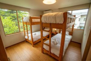 two bunk beds in a room with two windows at Serenity Chalet, walk to the lifts Happoone Ski Resort in Hakuba