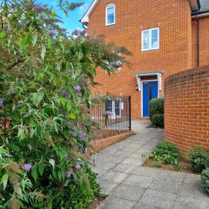 a brick house with a blue door and a bush at Spacious two bedroom apartment with one parking space in Thame