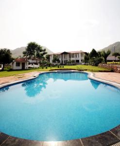 een groot blauw zwembad met huizen op de achtergrond bij Virat Resorts, Sariska Rajasthan in Bairāt