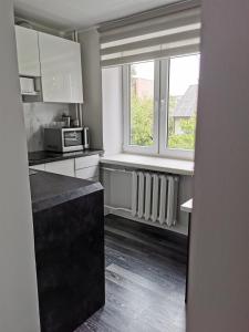 a kitchen with white cabinets and a window at Jaama Apartement in Valga