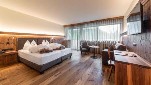 ein Hotelzimmer mit einem großen Bett und einem Schreibtisch in der Unterkunft Romantik Hotel Santer in Toblach