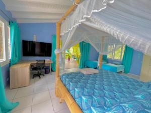 a bedroom with a canopy bed and a desk at Location privée tout équipé avec petit déjeuner inclus in Le Gosier