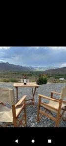 einen Tisch mit zwei Stühlen und eine Flasche Wein darauf in der Unterkunft Cabaña Abra del Monte Monohambiente in Cachí