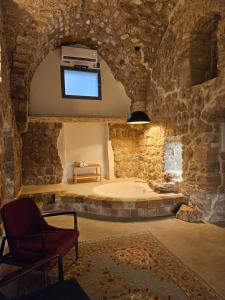 a large bathroom with a tub in a stone wall at Akotika boutique in Acre