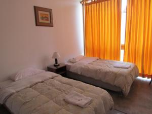 two beds in a room with orange curtains at Huanchaco Hostal in Huanchaco