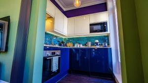 a small kitchen with blue and green walls at Stylish One Bedroom Flat in Kensingston London in London
