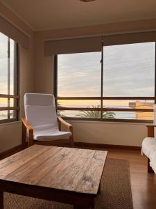 a living room with a table and a chair and a large window at Blumen Hotel in Concón