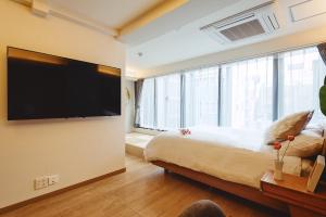 a bedroom with a large bed and a flat screen tv at 都心罕见东京奢华设计师Kcob带榻榻米 戴森&POLA顶级配置4分钟到东京站 20分钟到迪士尼 最大3人 in Tokyo