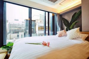 a bedroom with a large white bed with a large window at 都心罕见东京奢华设计师Kcob带榻榻米 戴森&POLA顶级配置4分钟到东京站 20分钟到迪士尼 最大3人 in Tokyo