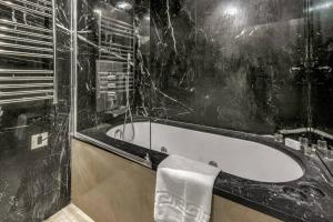 uma casa de banho preta com uma banheira e uma toalha em Modern One Bed Serviced Apartment in Chelsea em Londres