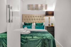 um quarto com uma cama grande e almofadas verdes em Modern One Bed Serviced Apartment in Chelsea em Londres