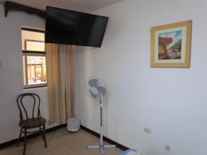 a room with a fan and a chair and a window at Huanchaco Hostal in Huanchaco