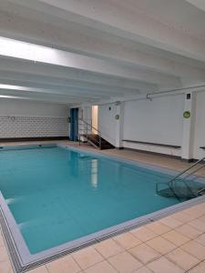 a large swimming pool with blue water in a building at App KLIF De Panne - top location & sea front !! in De Panne
