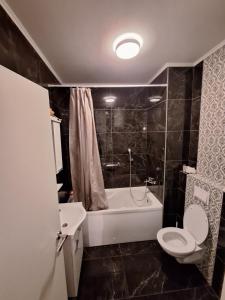a bathroom with a toilet and a tub and a sink at Elegantna oaza apartment in Banja Luka