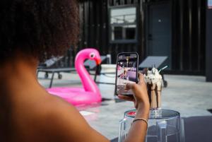 uma mulher a tirar uma fotografia a um flamingo rosa em Boxo Diani - Unique Beach Front Container Eco-Hotel em Diani Beach