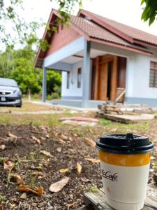 una tazza di caffè seduta su un tavolo di fronte a una casa di Dzanz Homestay a Kampong Pengkalan Maras