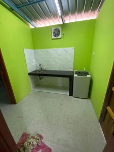 un bagno verde con lavandino e cestino di Dzanz Homestay a Kampong Pengkalan Maras