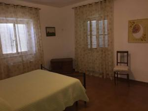 a bedroom with a bed and two windows and a chair at Casale Gli Ulivi in Orbetello