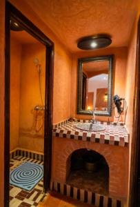 a bathroom with a fireplace with a sink and a mirror at Riad family in Merzouga