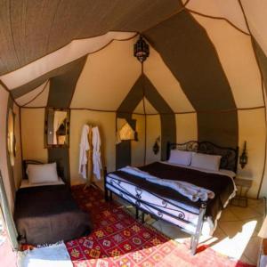 a bedroom with two beds in a tent at Merzouga luxury magic nights in Merzouga