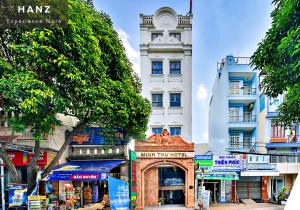 HANZ Minh Thu Hotel Tan Binh في مدينة هوشي منه: مبنى ابيض طويل مع برج ساعه