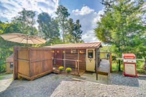 a wooden cabin with an umbrella and a grill at Sevierville Studio Cabin Rental with Private Hot Tub in Sevierville