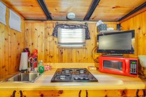a kitchen with a stove and a microwave and a sink at Sevierville Studio Cabin Rental with Private Hot Tub in Sevierville
